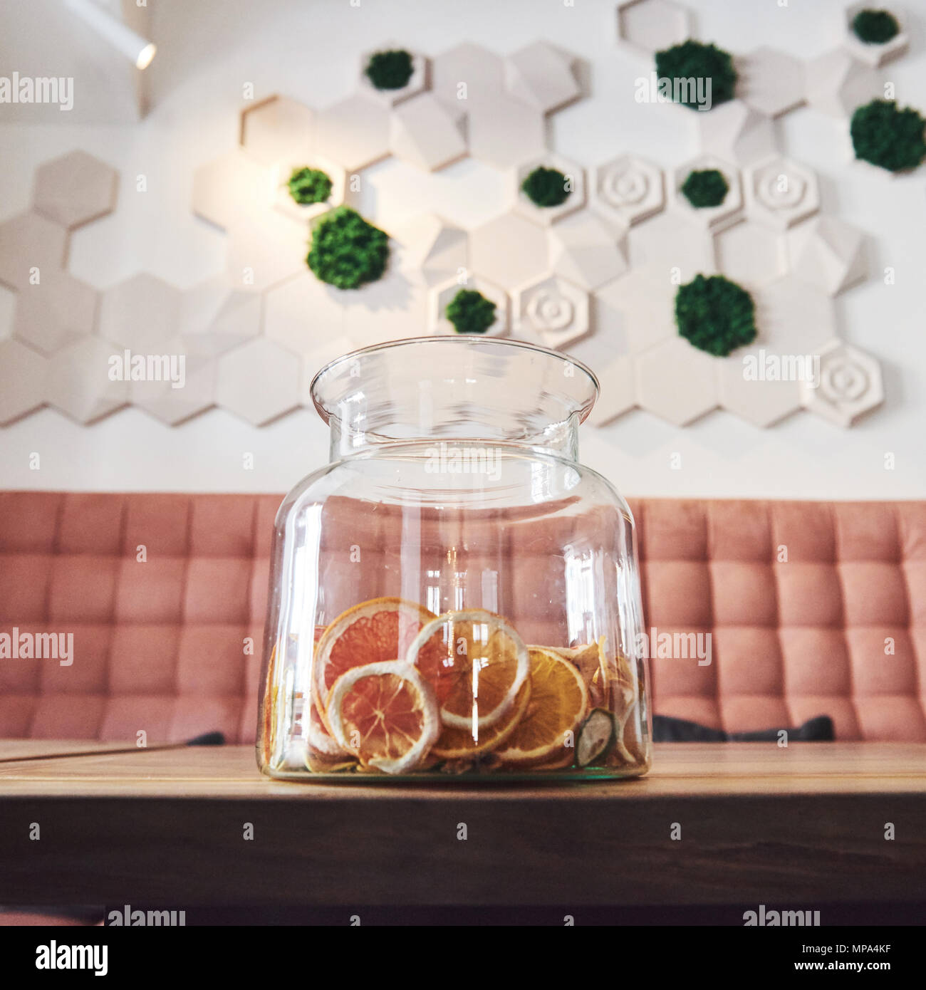 Essiccato arancia candita, lime e limone le ruote nel grande contenitore di vetro con contenuti disposti anche su butcher blocco attorno al vaso con lo zucchero greggio e il coperchio in metallo Foto Stock