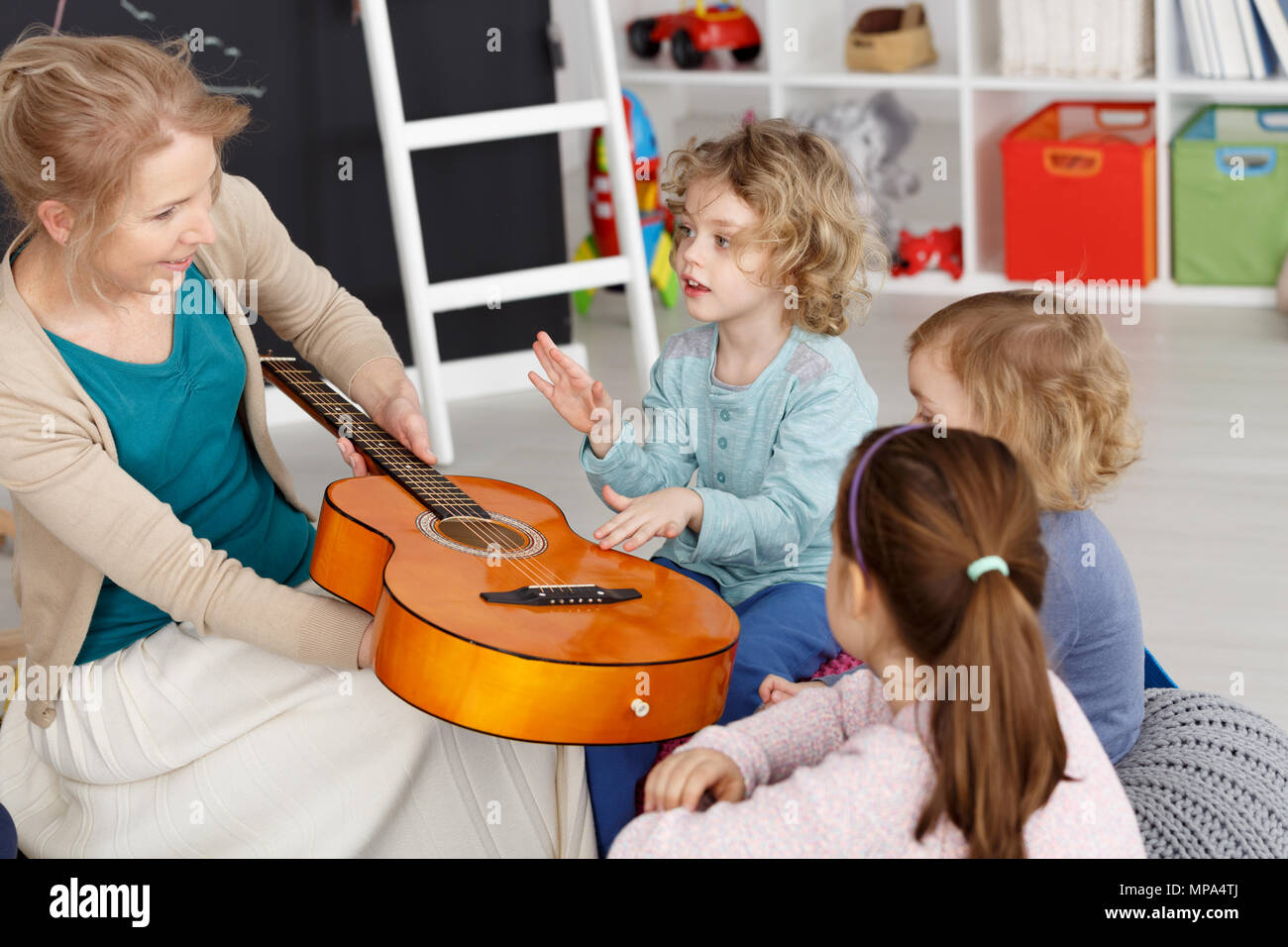 Giovane insegnante avente lezione di musica con bambini piccoli nella scuola materna Foto Stock