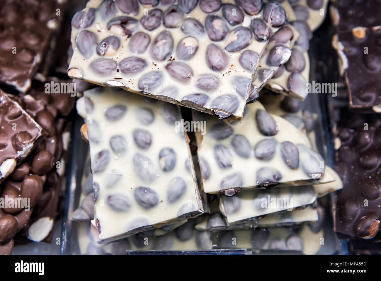Macro closeup di pelo di molti il cioccolato bianco pezzi pezzi bar con arachidi, mandorle sul display del vassoio nel negozio di caramelle chocolatier shop Foto Stock