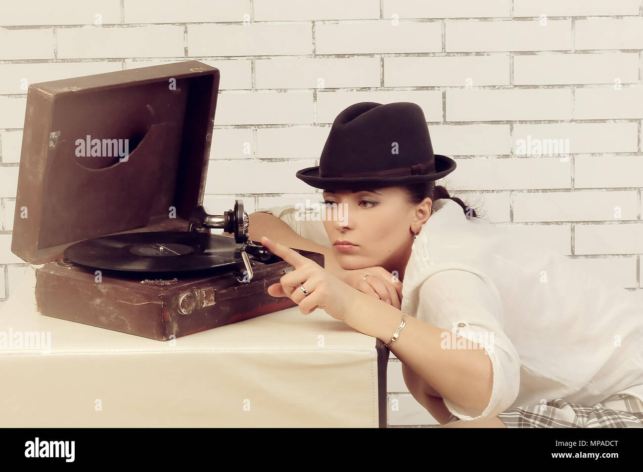 Ritratto di una donna in un cappello vicino il grammofono, nei pressi di un bianco muro di mattoni Foto Stock