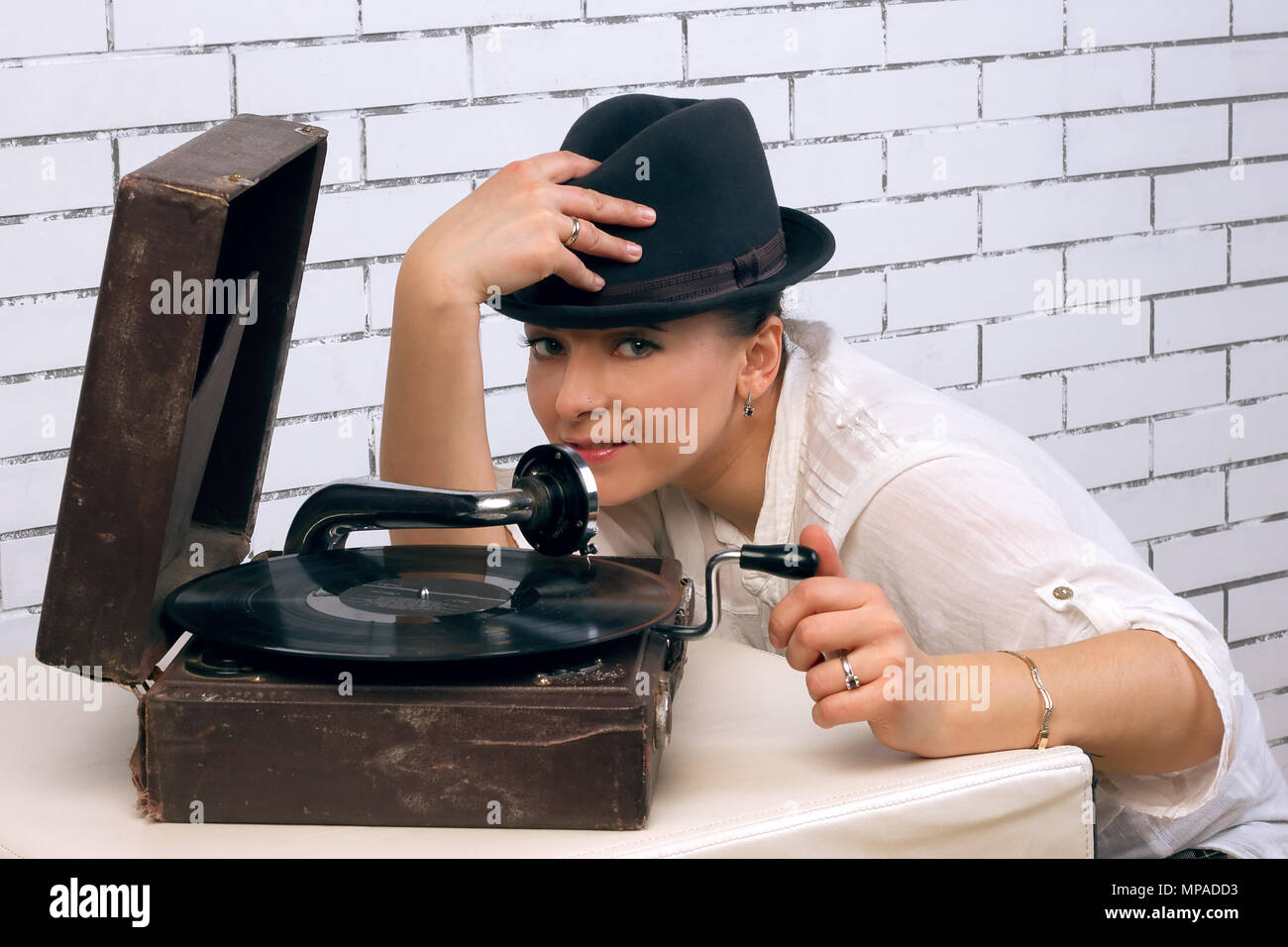 Ritratto di donna nel cappello per il grammofono, vicino il bianco muro di mattoni Foto Stock