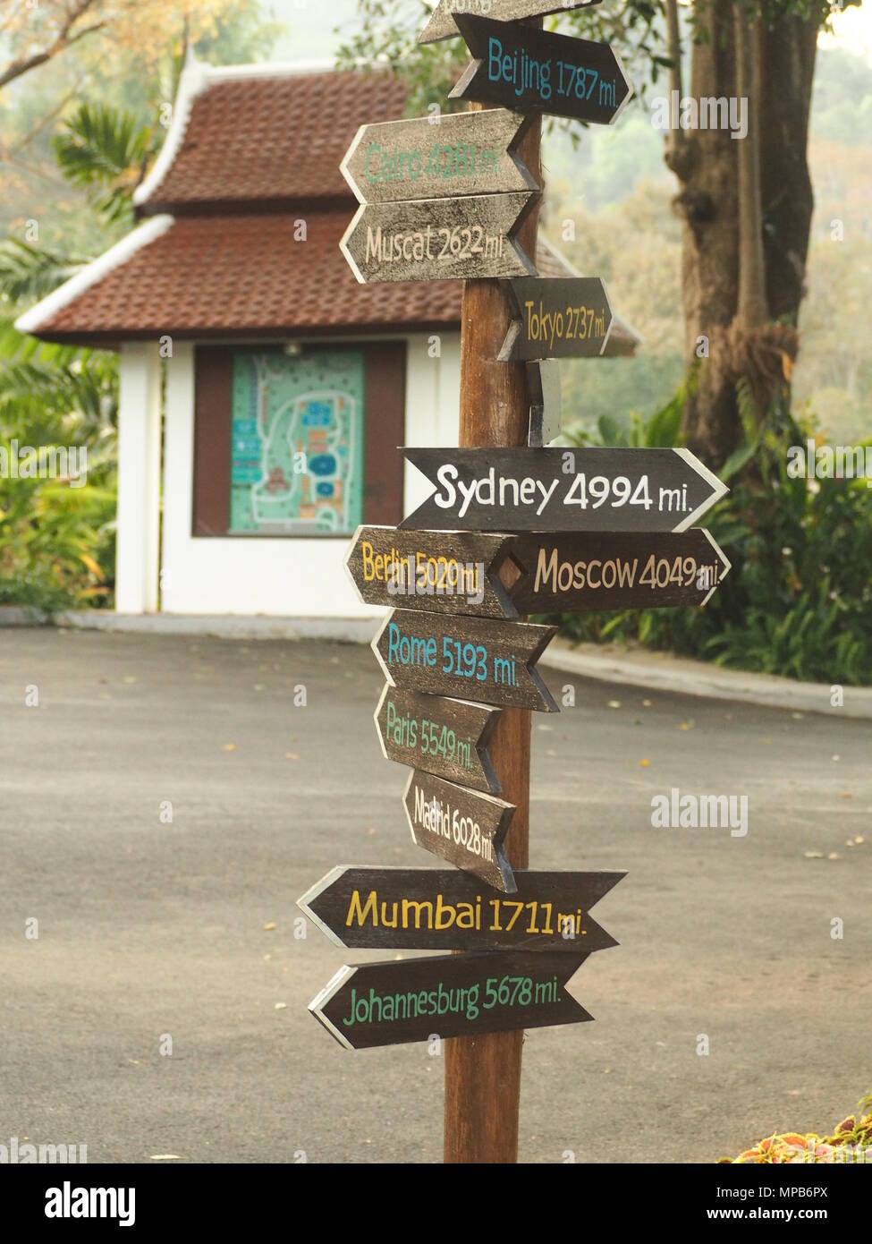 Un cartello di legno con i nomi colorati globale di città di tutto il mondo e la distanza da loro. Foto Stock