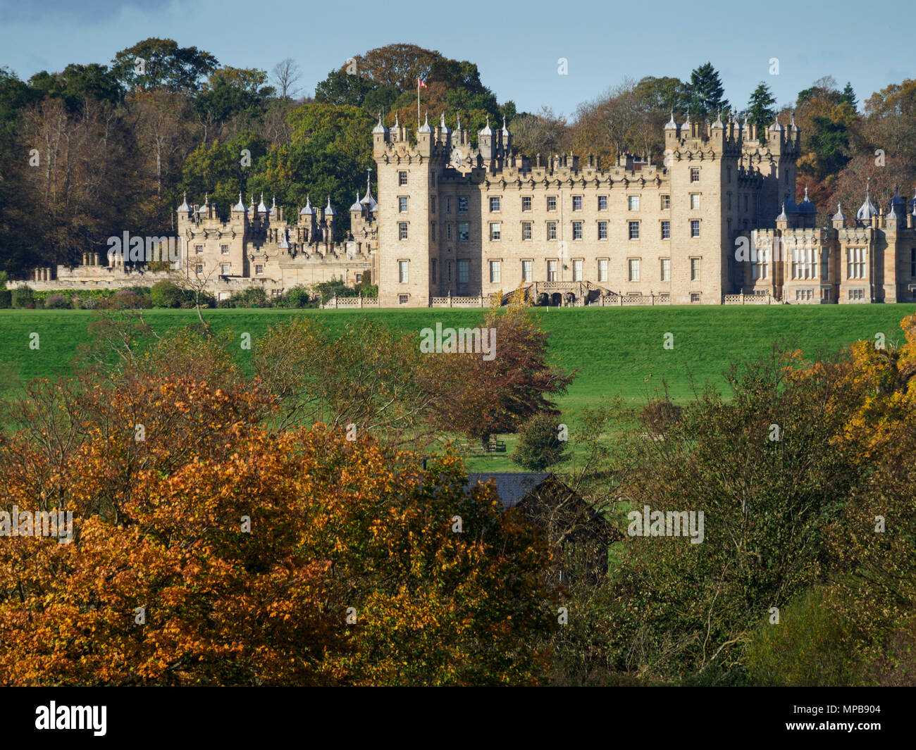 Il castello di pavimenti, a Kelso, sede del duca di Roxburghe, countryu casa aperta al pubblico. Con l'autunno alberi, visto oltre il Tweed River. Foto Stock