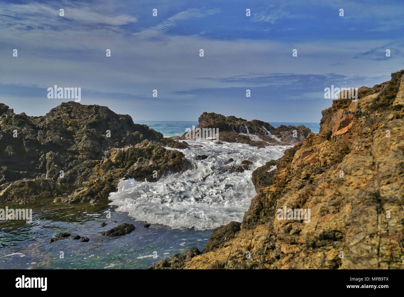 Le onde si riversano le rocce in acque cristalline del Matapouri mermaid piscine in Nuova Zelanda Foto Stock
