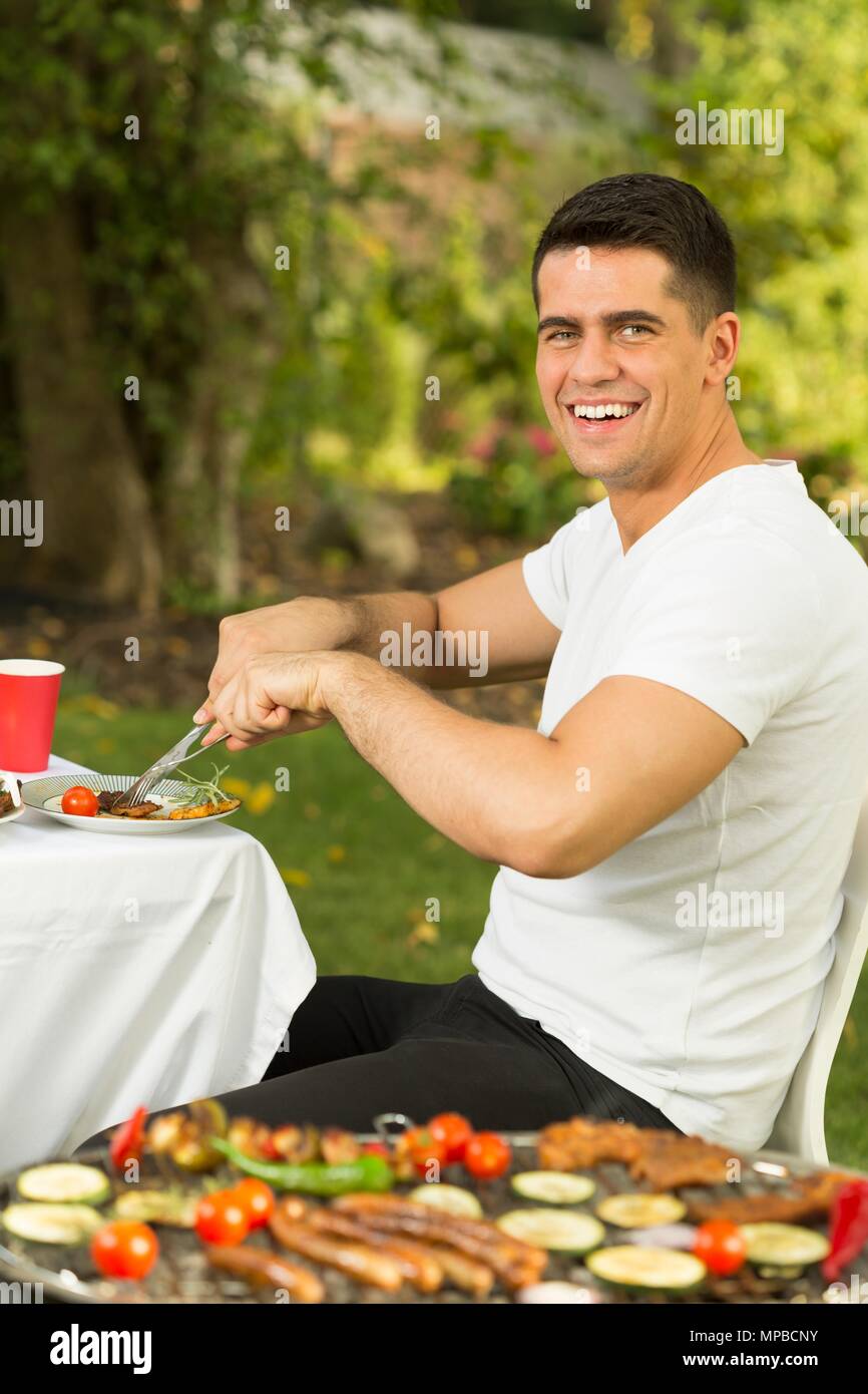 L'uomo mangiare grigliata durante il barbecue party Foto Stock