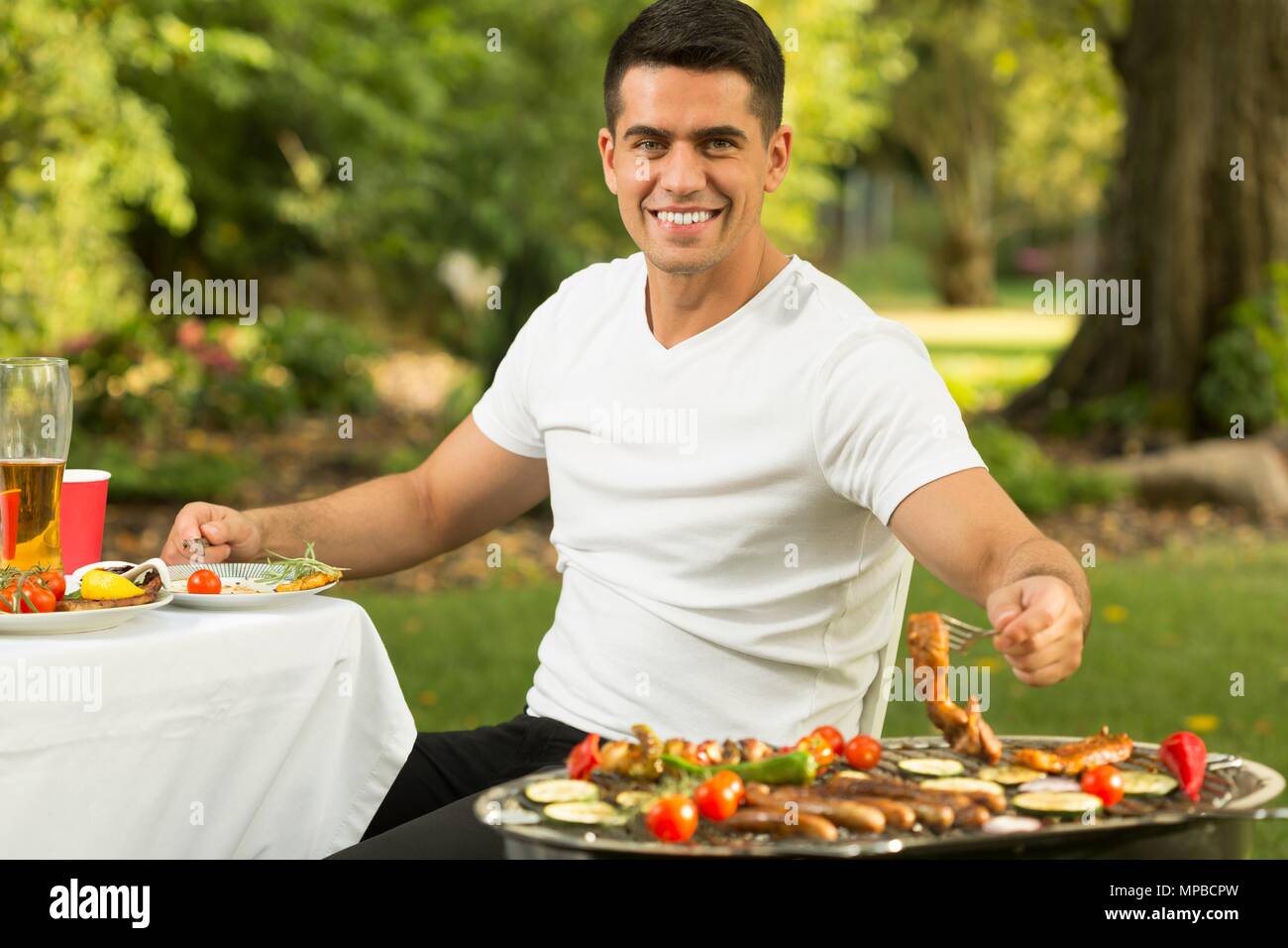 Giovane uomo mangiare il cibo gustoso su barbecue party Foto Stock