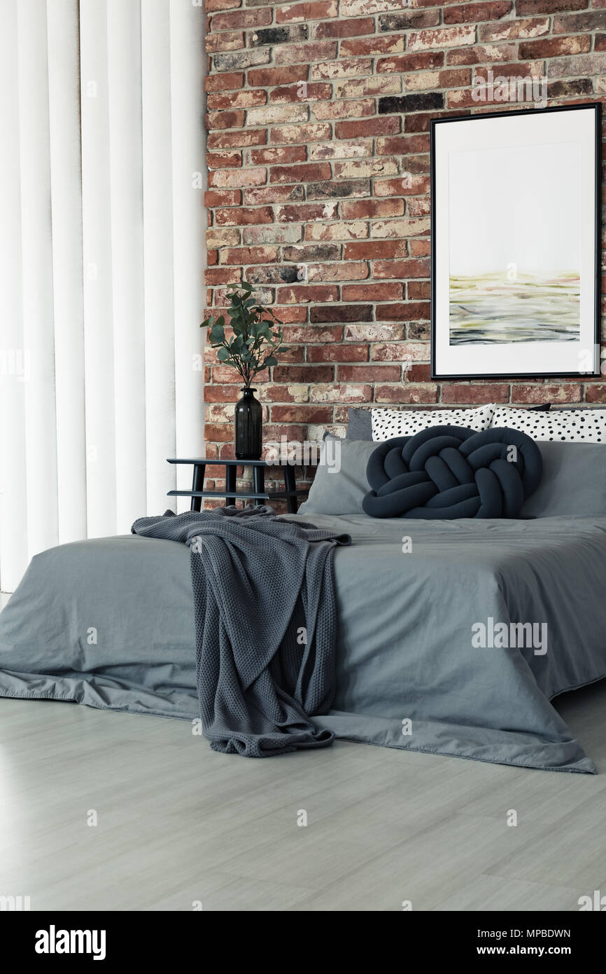 Dark coperta e cuscino nodo su grigio letto king size nella camera da letto  con dipinto sul muro di mattoni Foto stock - Alamy
