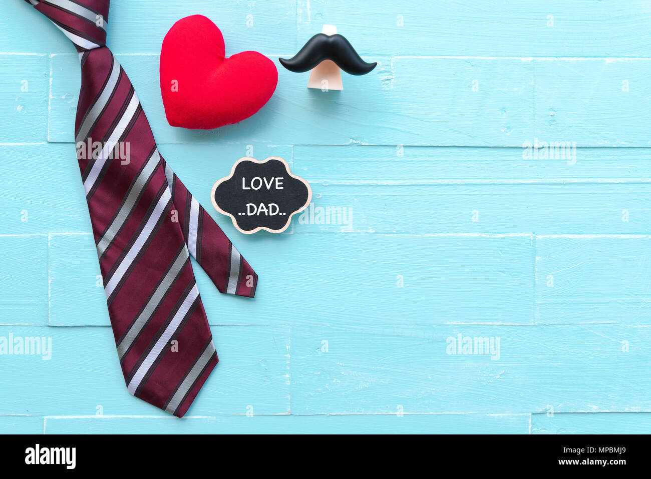 Felice giorno padri concetto. Cravatta rossa, mano cuore rosso i baffi con amore il papà del testo in blu chiaro pastello tavolo in legno sfondo. Foto Stock