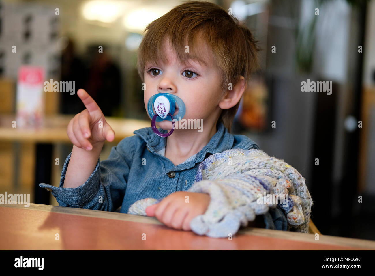 18 mesi di età bambino seduto nella sedia alta con fantoccio e coperta di comfort Foto Stock