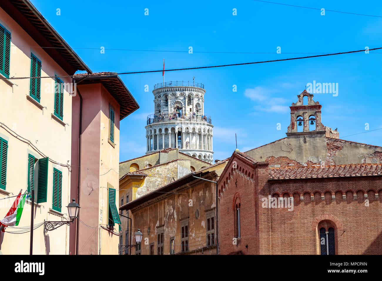 La Torre Pendente di Pisa si vede in mezzo alle tipiche costruzioni locali contro un blu cielo privo di nuvole Foto Stock