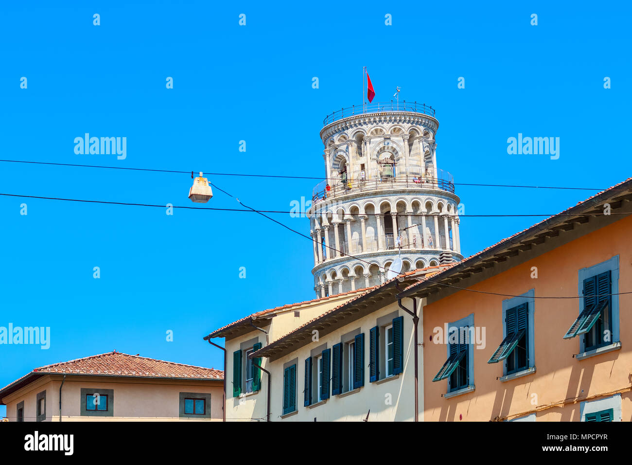 La Torre Pendente di Pisa si vede in mezzo alle tipiche costruzioni locali contro un blu cielo privo di nuvole Foto Stock