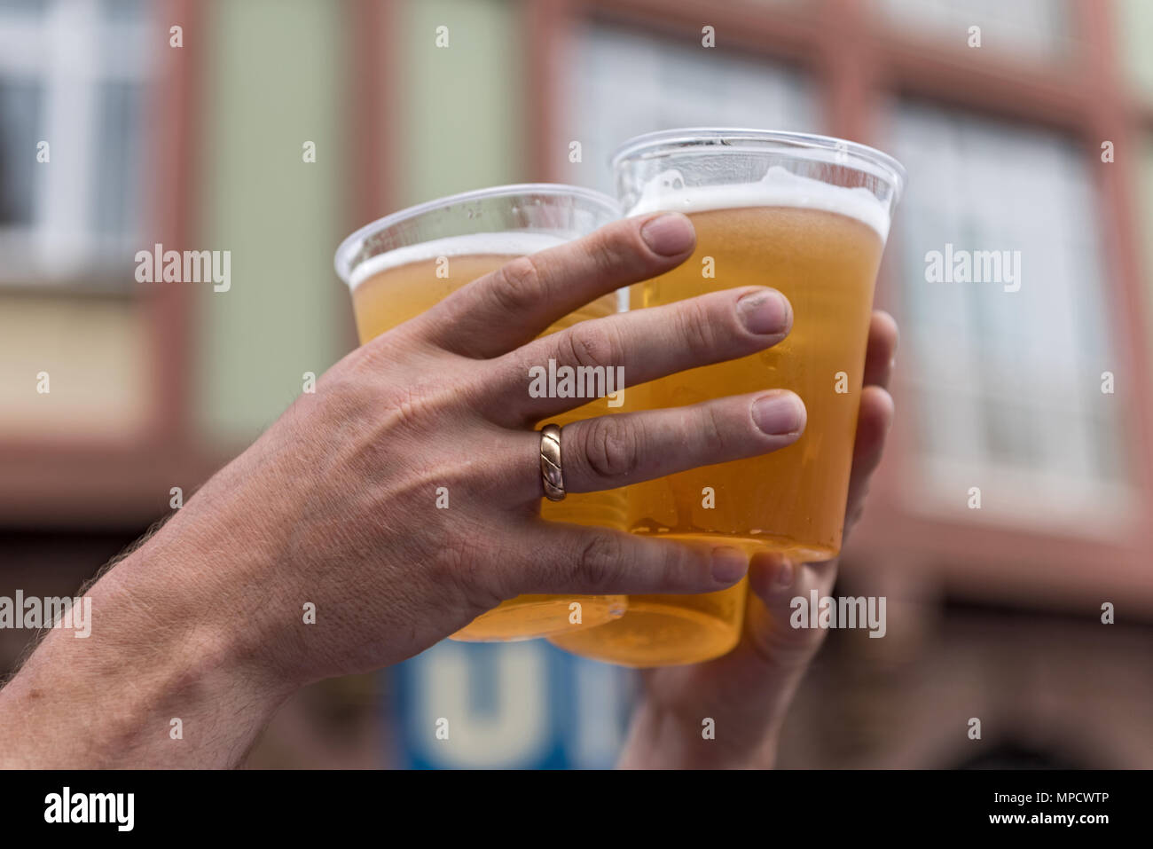 Due mani e tre bicchieri di plastica con la birra Foto Stock