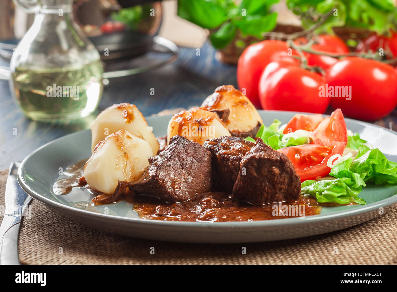 La carne di maiale spezzatino di carne servito con patate e insalata di verdure su una piastra. Vista laterale. Foto Stock