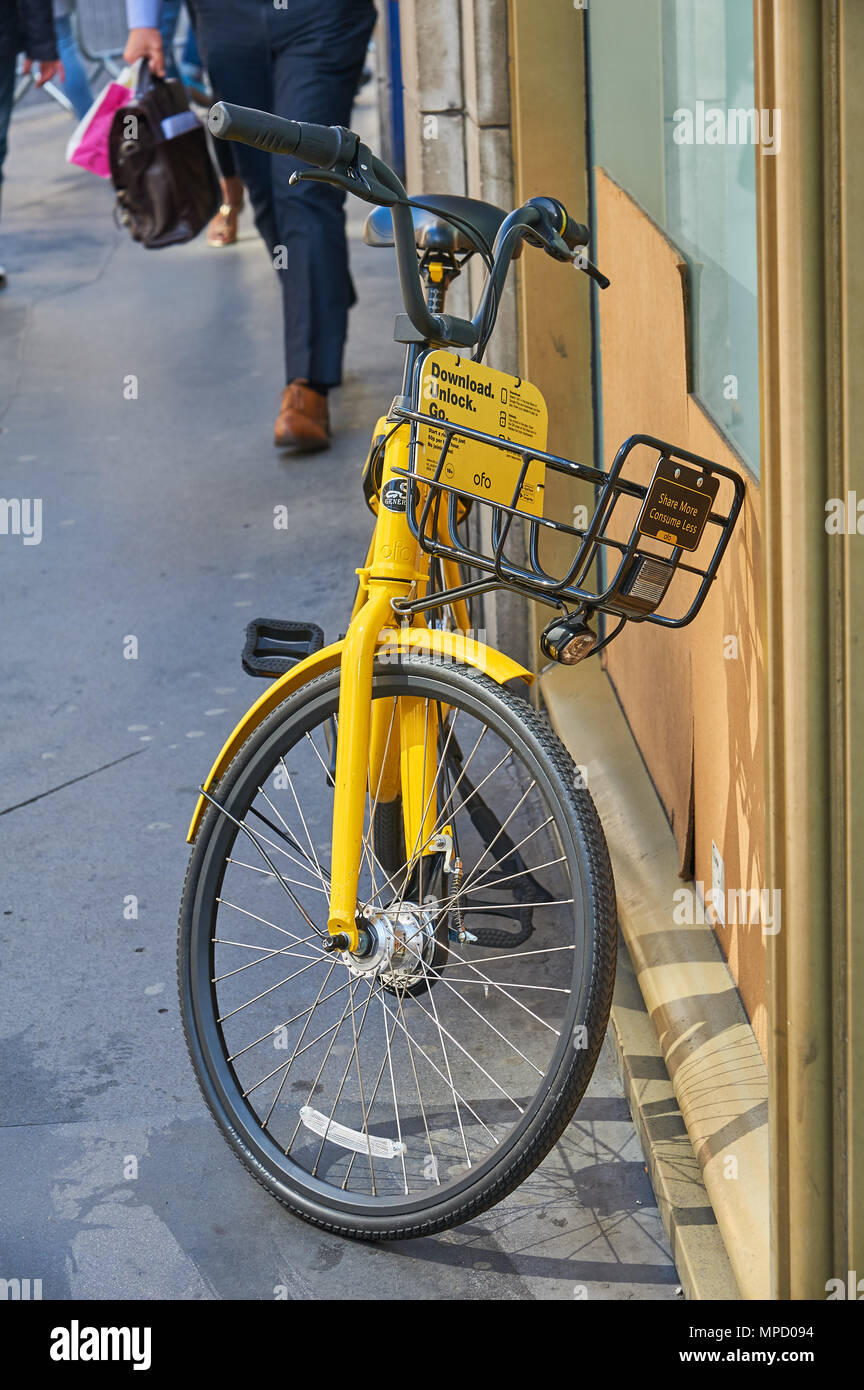 Giallo dockless nolo bici lasciate al di fuori di un edificio in un ambiente cittadino Foto Stock
