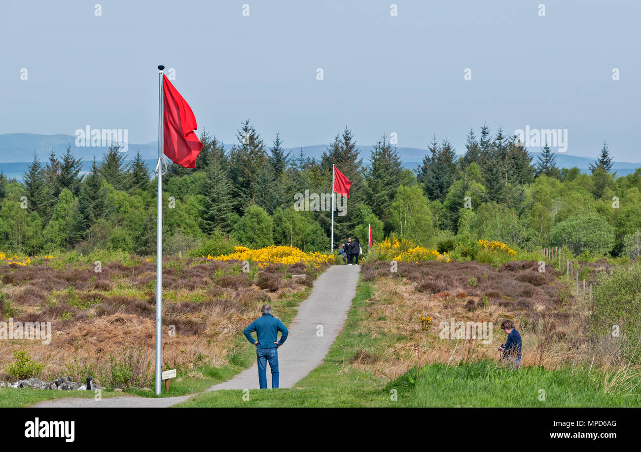 Il campo di battaglia di Culloden Moor o INVERNESS Scozia VISTA DEL CAMPO DI BATTAGLIA Tipiche bandiere rosse marcatura della linea inglese e turisti sul percorso a piedi Foto Stock