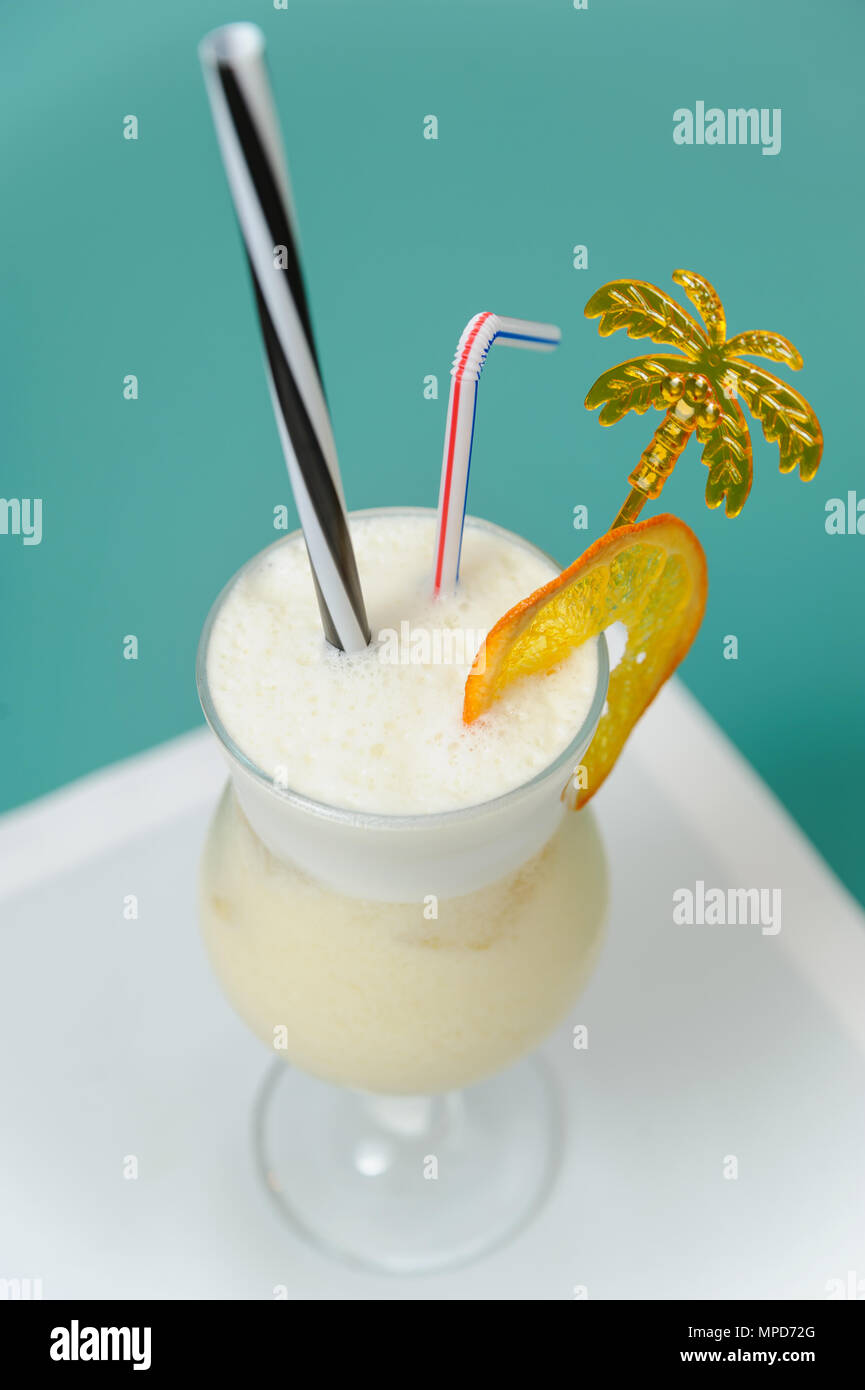 Frullato in un vetro decorato con fettine di arancia, strisce e stick in forma di palme. Foto Stock