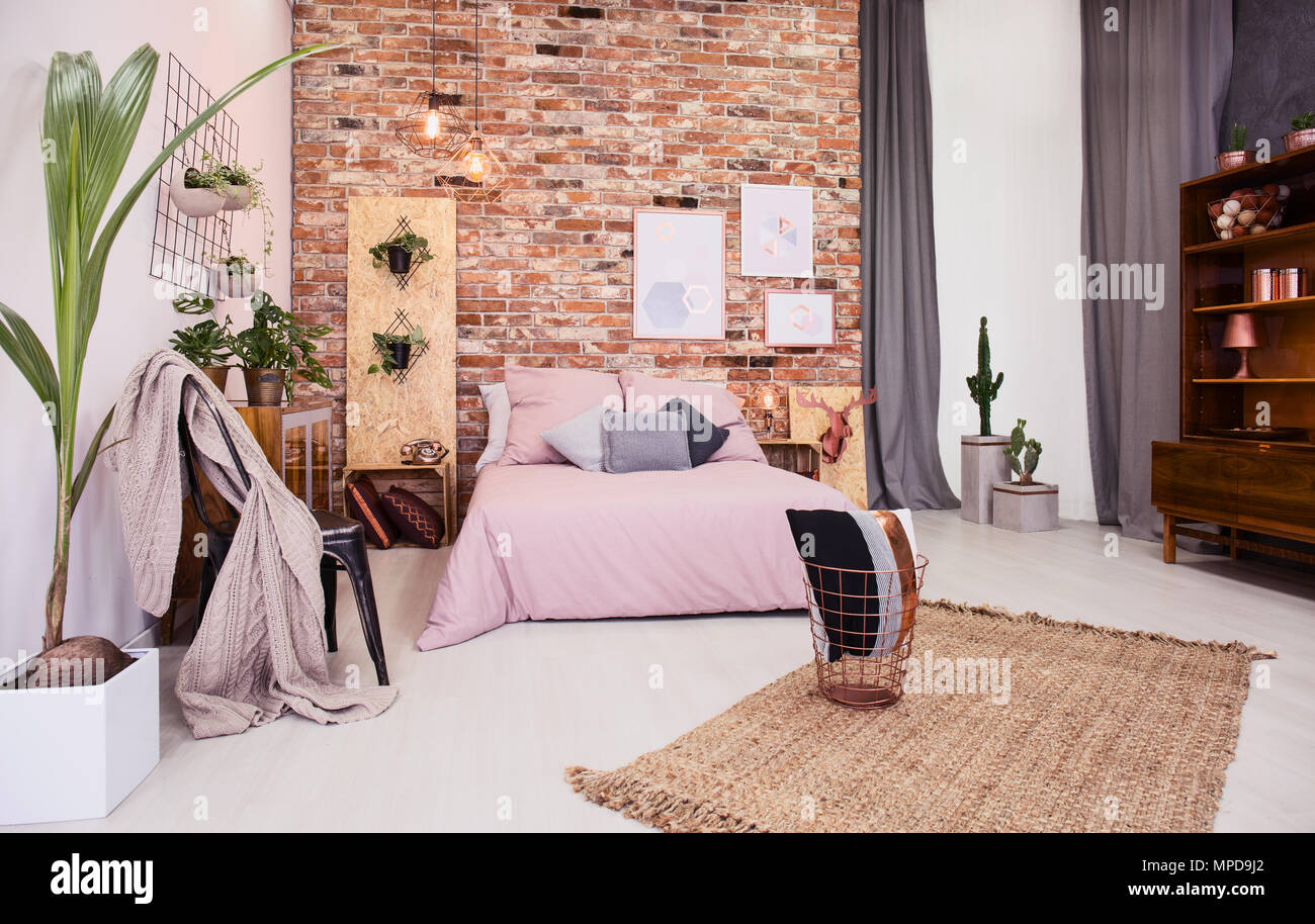 Rosa polveroso camera da letto con letto matrimoniale e il rosso un muro di mattoni Foto Stock