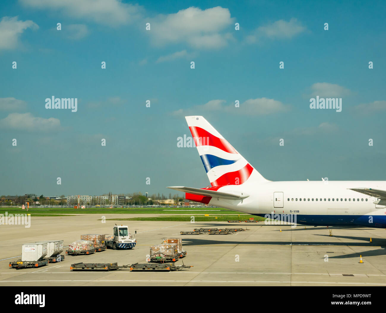 British Airways piani, compreso un Boeing 777 su airport grembiule con veicoli aeroportuali, terminale 5, l'aeroporto di Heathrow di Londra, Inghilterra, Regno Unito Foto Stock