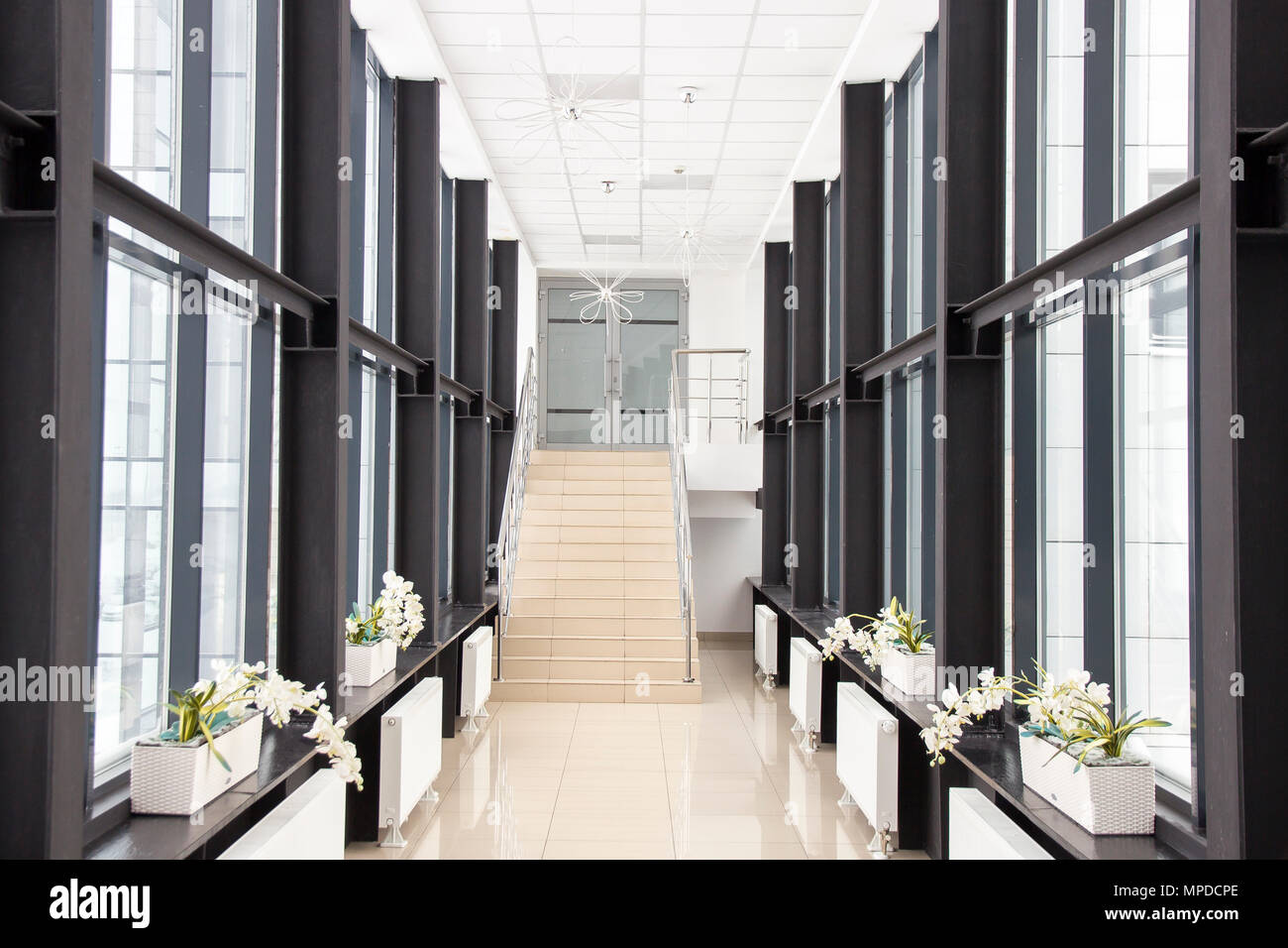 Centri di Business corridoio con finestre su entrambi i lati, con i fiori sul davanzale, le scale che portano al secondo piano, senza persone Foto Stock