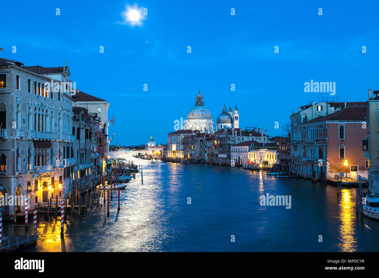 Luna piena al blue ora sul Grand Canal, Venezia, Veneto, Italia con la Basilica di Santa Maria della Salute e una riflessione sull'acqua Foto Stock