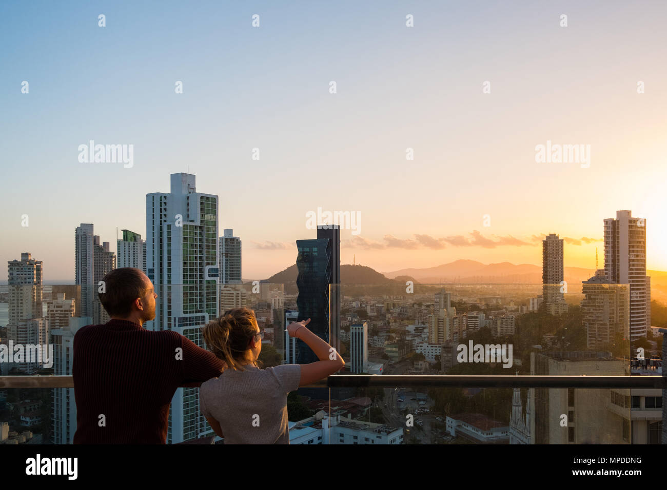 Giovane guardando al di sopra dello skyline della città con il Cielo di tramonto dal grattacielo bilding Foto Stock