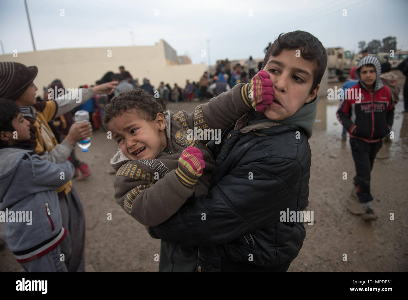 I bambini in attesa in una stazione di lavorazione per gli sfollati interni prima di essere trasportati in campi per rifugiati nei pressi di Mosul, Iraq, Marzo 03, 2017. (U.S. Foto dell'esercito da Staff Sgt. Alex Manne) Foto Stock