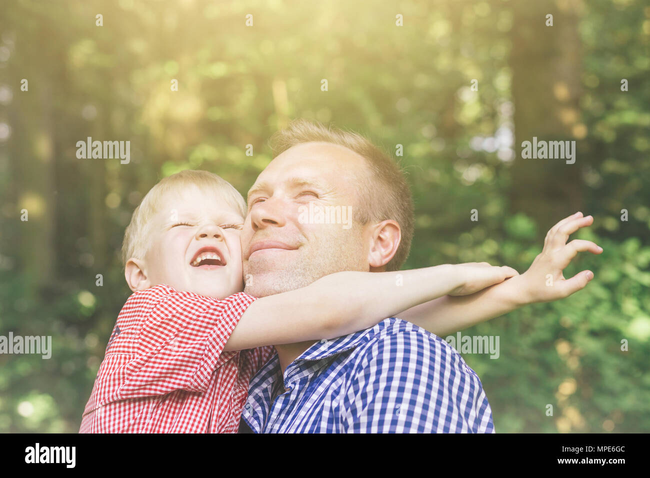 Padre e Figlio abbraccia, sorridente e crogiolarvi al sole. Concetto di mascolinità. Emotional ritratto di famiglia. Foto Stock
