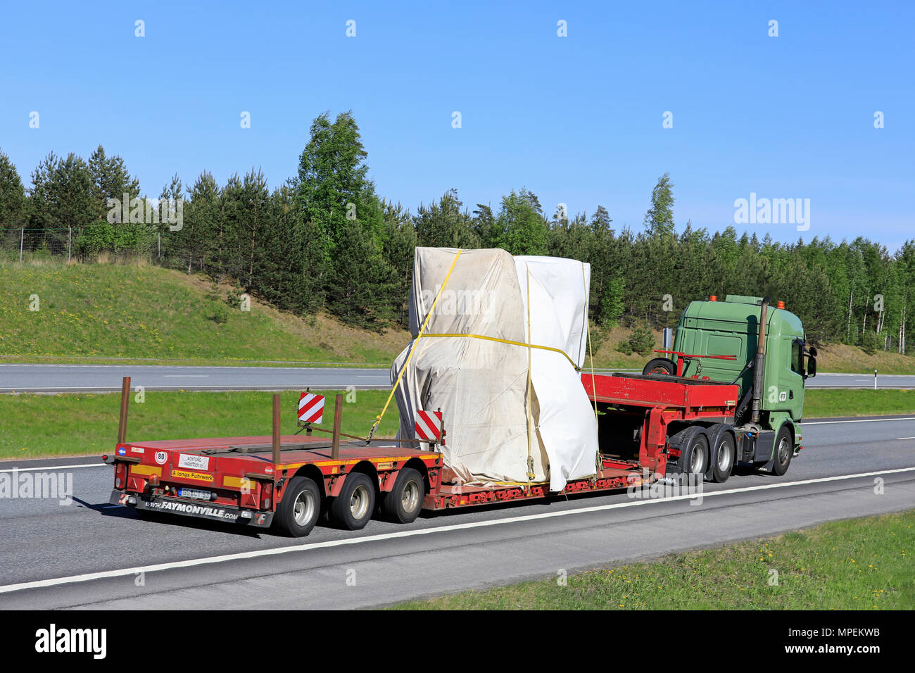 Green Scania semi rimorchio cale telone coperti oggetto industriale come carico a lungo sulla superstrada estate in una giornata di sole. Vista laterale. Salo, Finlandia - 18 Maggio Foto Stock