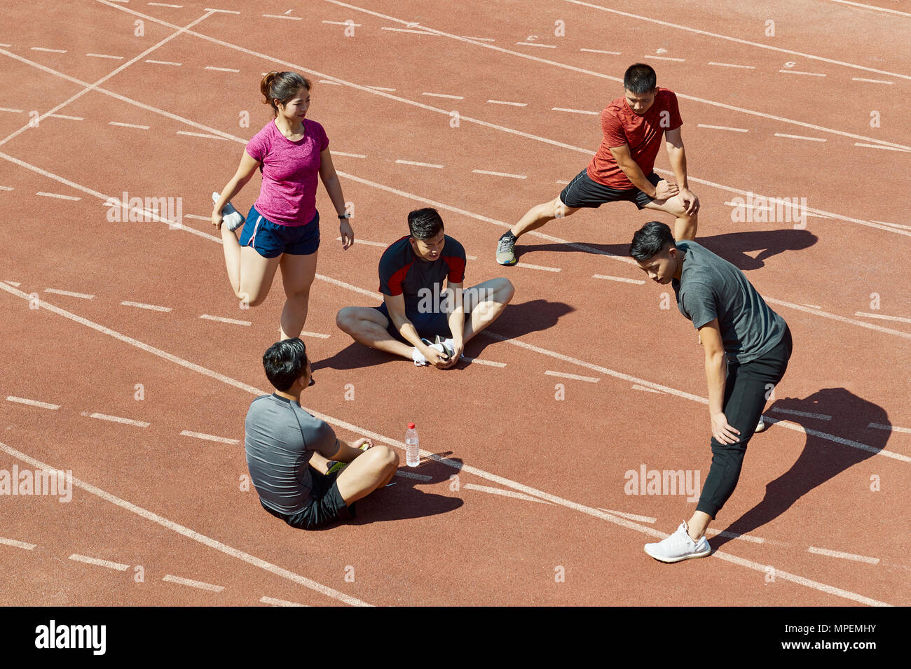 Un gruppo di giovani atleti asiatici stretching rilassante sulla via prima del training. Foto Stock