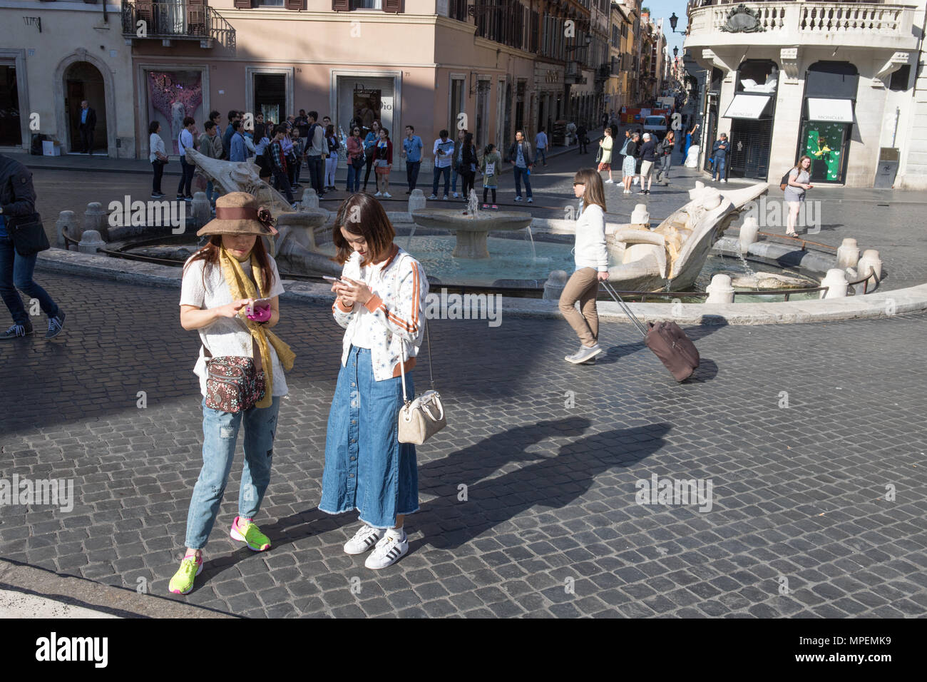 Due donne asiatiche turisti alla ricerca permanente di smartphone in Piazza di Spagna, Roma Italia Foto Stock