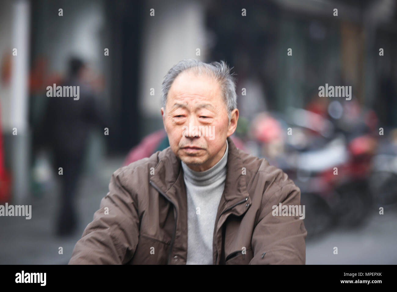 Un cinese vecchio uomo in sella a una moto in Hangzhou, Cina Foto Stock