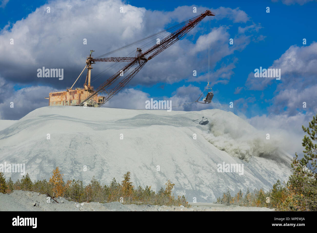 Large open-pit mining escavatore è il dumping di prodotti dei rifiuti in discariche sullo sfondo di un cielo nuvoloso Foto Stock