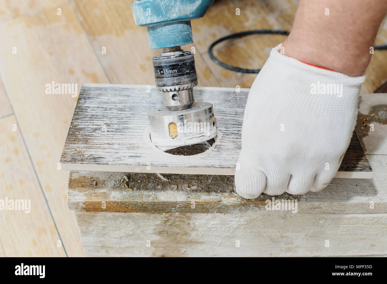 Installatore scolpisce un foro nella mattonella usando una corona diamantata. Foto Stock