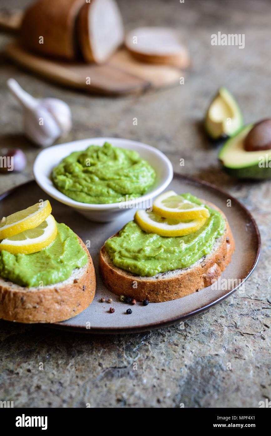 Sana diffusione di avocado con aglio sul frumento integrale fetta di pane Foto Stock