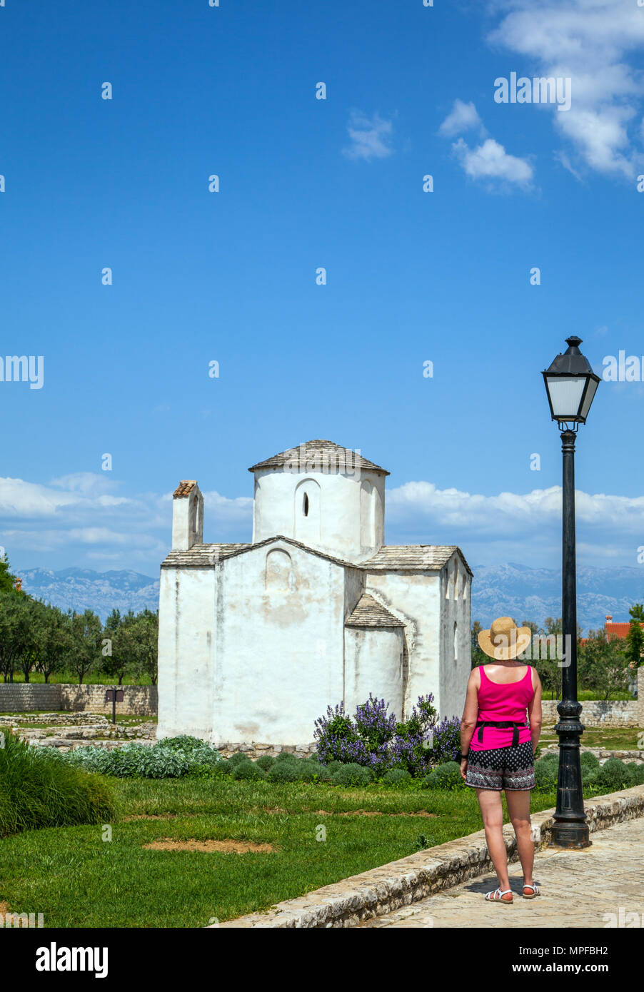Donna in hat visualizzazione della chiesa di Santa Croce presso il resort croato di Nin Zada Croazia, che si ritiene essere la più piccola cattedrale del mondo Foto Stock