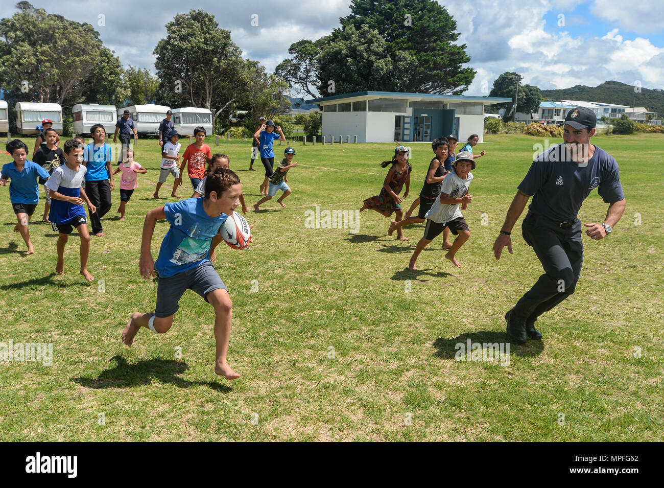 Royal New Zealand Navy Petty Officer subacqueo Alan Holland, assegnato al Royal New Zealand Navy Littoral Warfare unità, gioca a rugby con un gruppo di bambini della scuola Whangaruru durante l'esercizio fulcro nella baia di blando, Nuova Zelanda, Feb 17, 2017. Esercitare il fulcro è un combinato-esercizio congiunto che integra U.S. I marinai della marina militare e Marines dall'eliminazione degli ordigni esplosivi unità mobili con i membri del servizio dal Royal New Zealand Navy e la Royal Australian Navy. (U.S. Navy combattere la foto della telecamera tramite la comunicazione di massa specialista di terza classe Alfred A. Coffield) Foto Stock