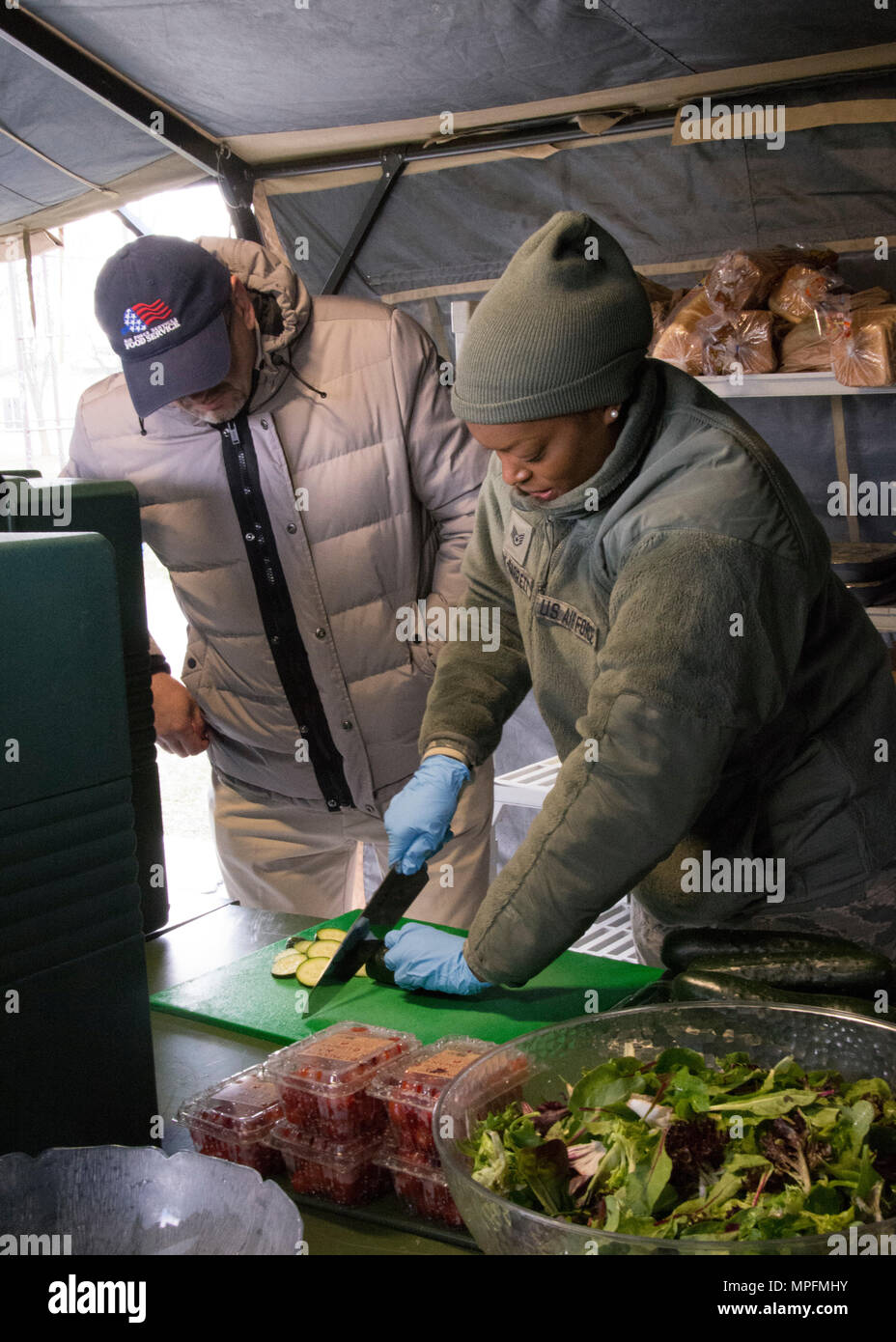 David Richmond, rappresentante con il National Restaurant Association, orologi Staff Sgt. Mercedes McCoy-Garrett, servizi alimentari specialista, 512th affari Memorial Squadron, tritare un zucchine dopo il suo insegnamento corretto tecniche di taglio mentre in lizza per il 2017 John L. Hennessy Award alla Dover Air Force Base, Del., 3 marzo 2017. La Hennessy premio riconosce l'eccellenza nella ristorazione in più rami militari. (U.S. Air Force foto / Renee M. Jackson) Foto Stock