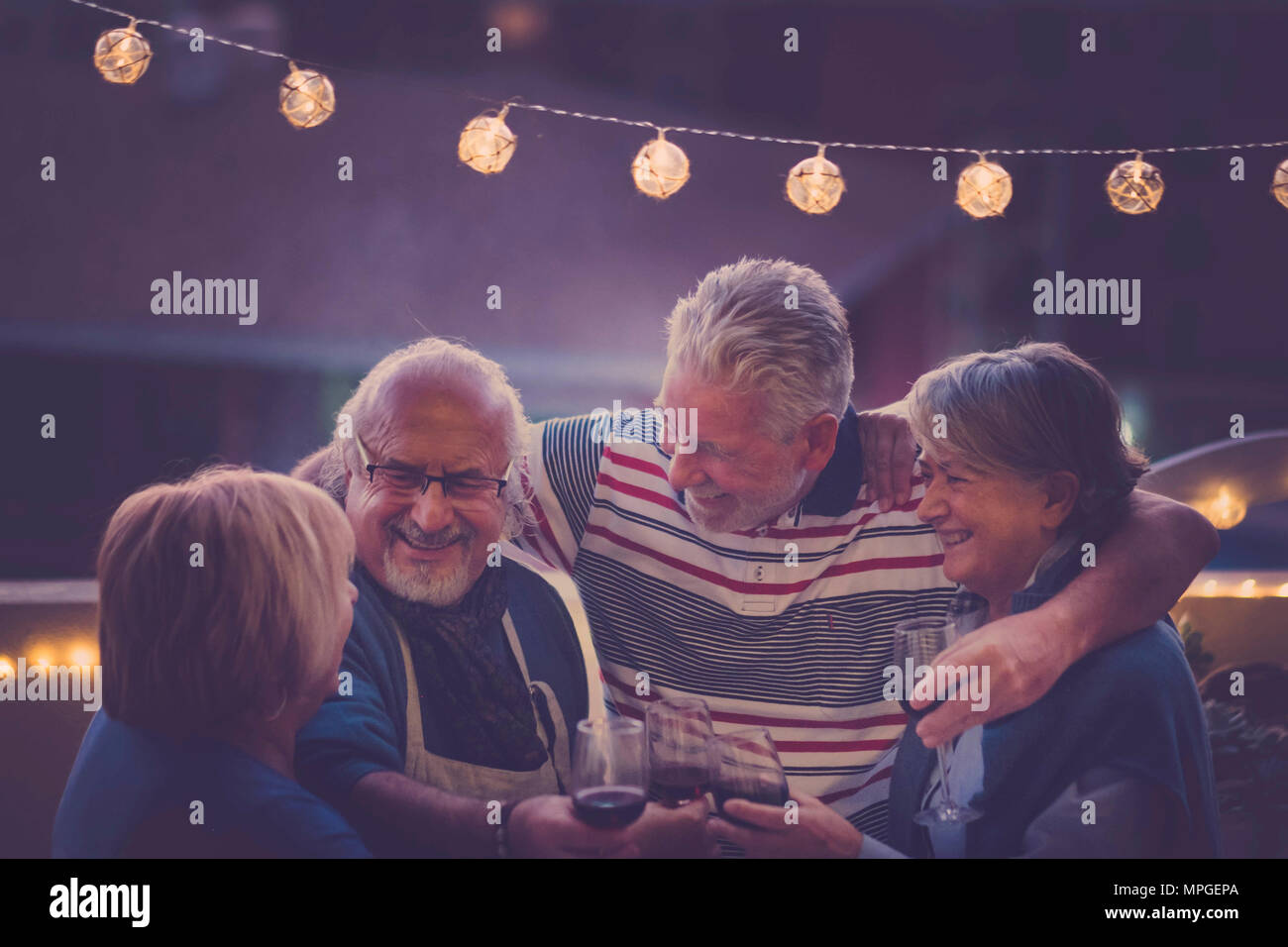 Focus sull'uomo. gruppo di anziani di età adulta facendo parte della notte sul tetto di casa. abbraccio tutti insieme e sorridere e ridere per un attività di nizza Foto Stock