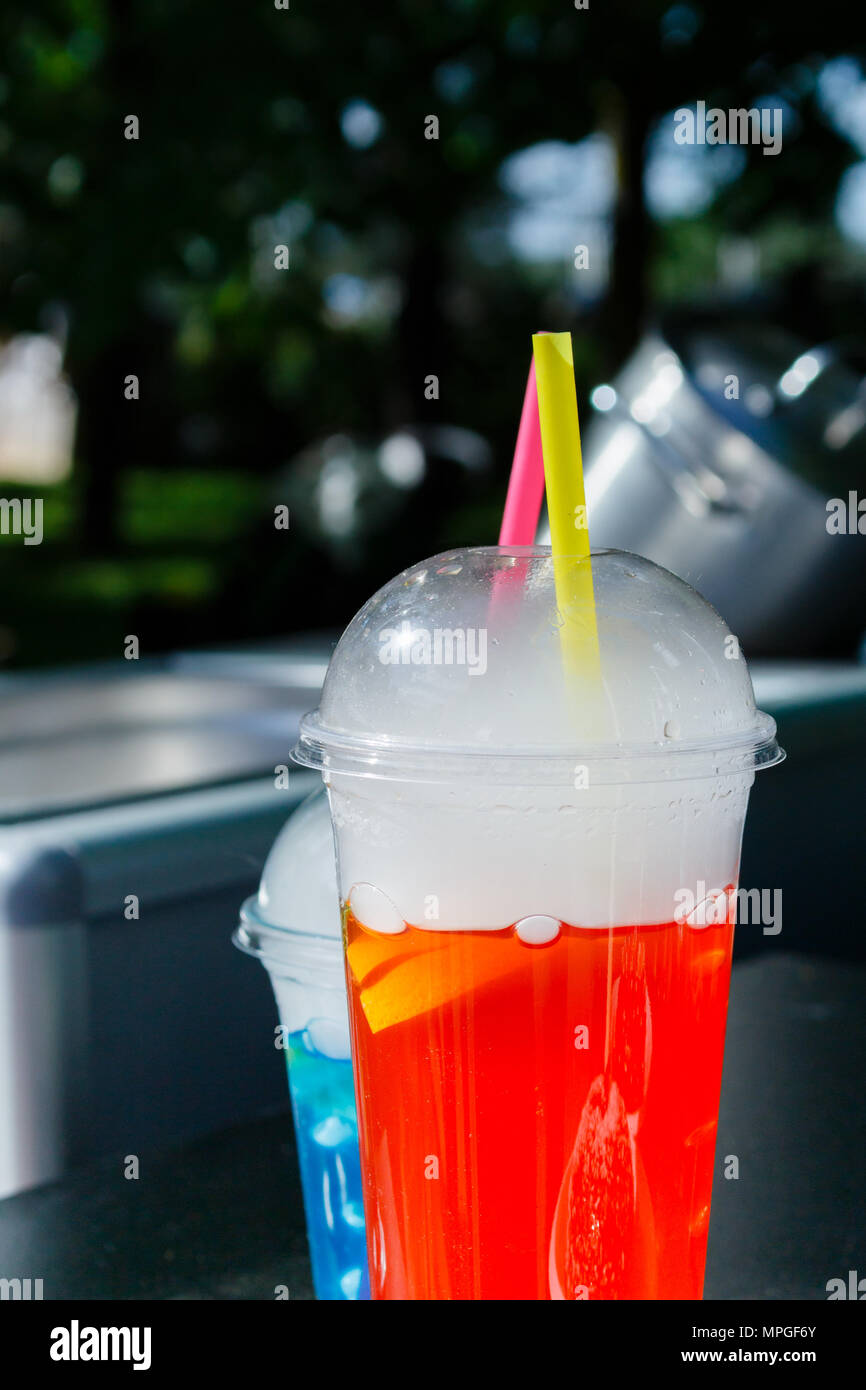 I bicchieri di plastica con spumante frutta fresca limonate con paglia sulla street food festival luminosa giornata soleggiata, sfondo verde scuro Foto Stock