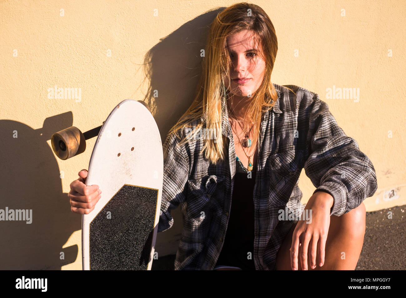 Libertà il concetto di stile di vita alternativo il biondo viaggiatore femmina sedersi con uno skateboard sotto il sole in vacanza. outdoor activity tempo libero con n Foto Stock
