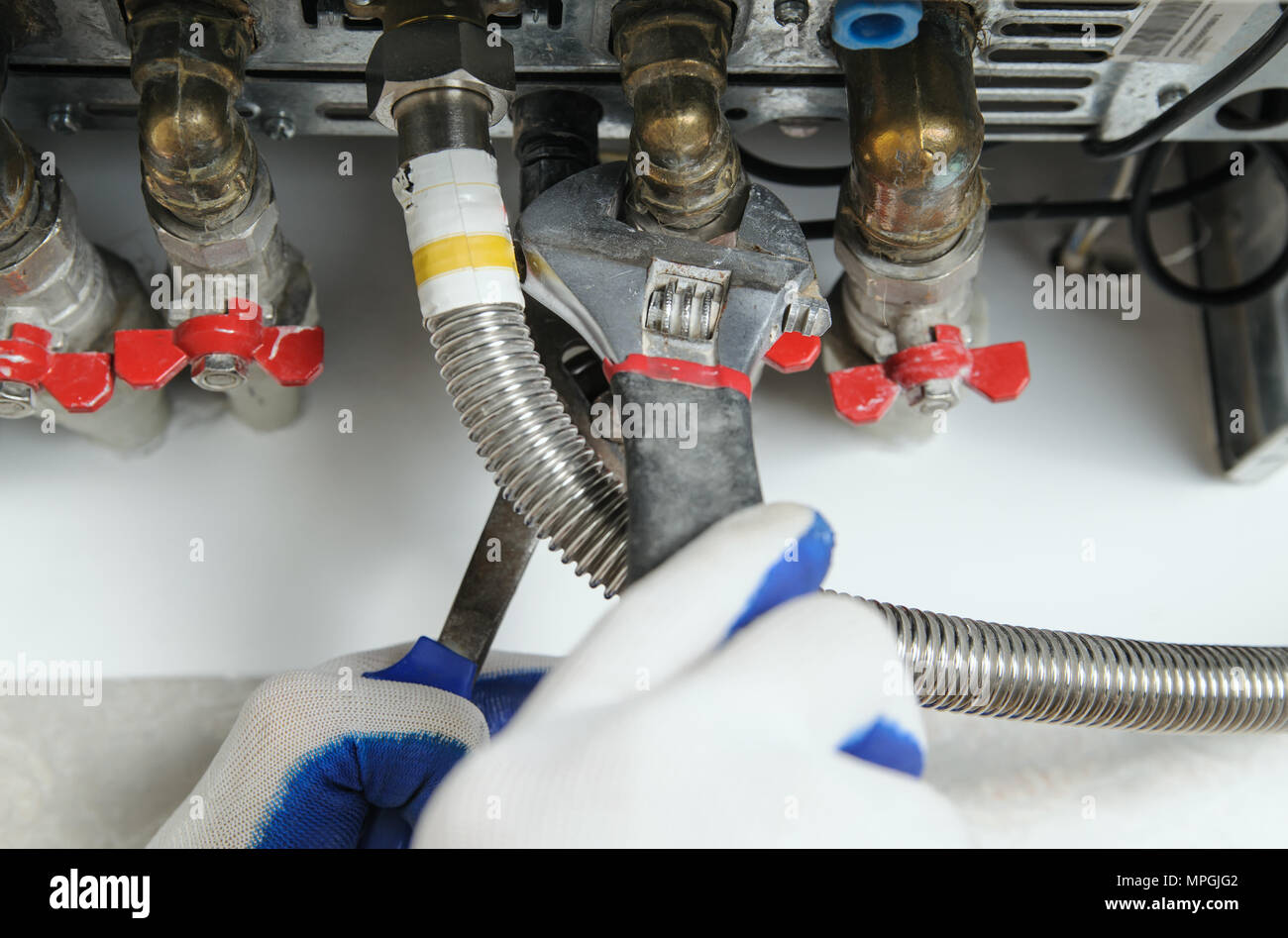 Plumber attribuisce alla canalizzazione caldaia a gas utilizzando una chiave regolabile. Foto Stock