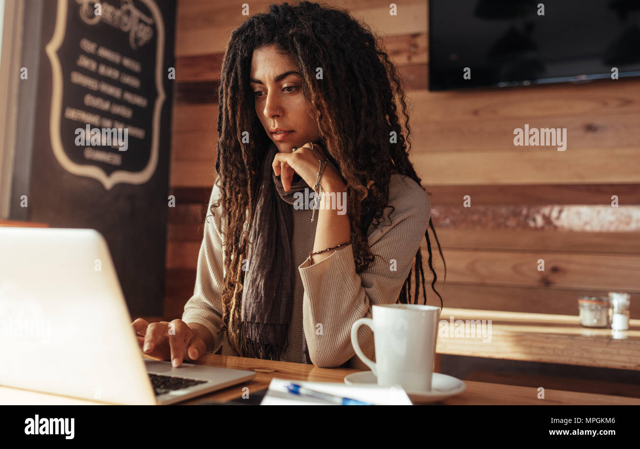 Donna seduta presso un ristorante tabella lavorando sul computer portatile. Libero professionista in seduta cafe con un caffè lavorando sul computer portatile. Foto Stock
