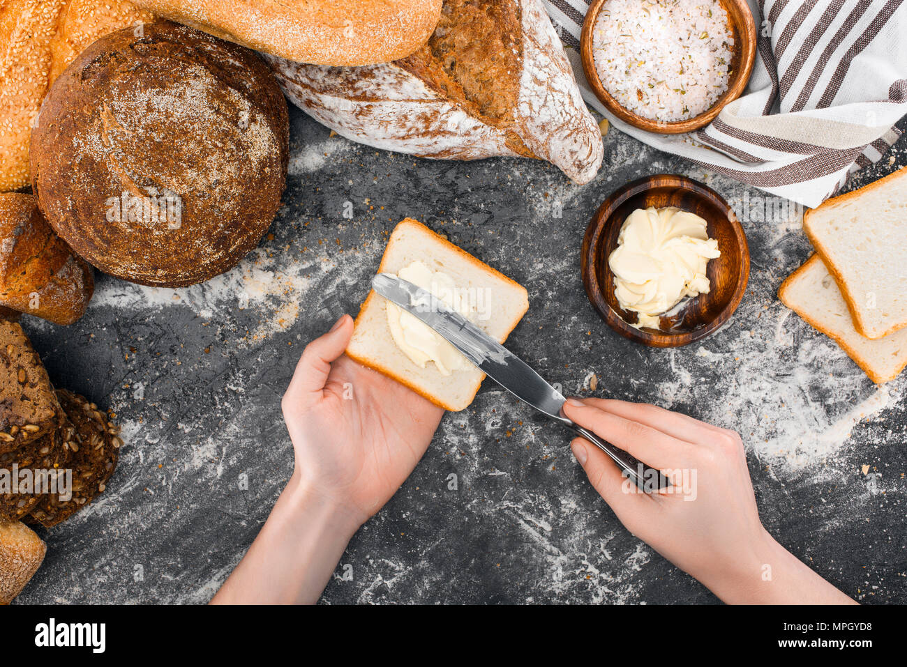 Persona diffusione di burro sul pane tostato Foto Stock
