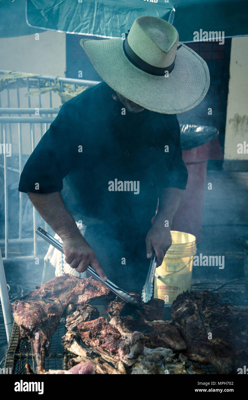 Giovani chef bianco con il nero grembiule e cappello in piedi vicino al braciere con carbone. Foto Stock