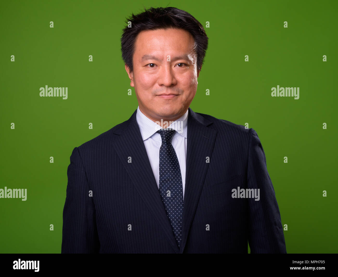 Maturo imprenditore giapponese contro lo sfondo di colore verde Foto Stock