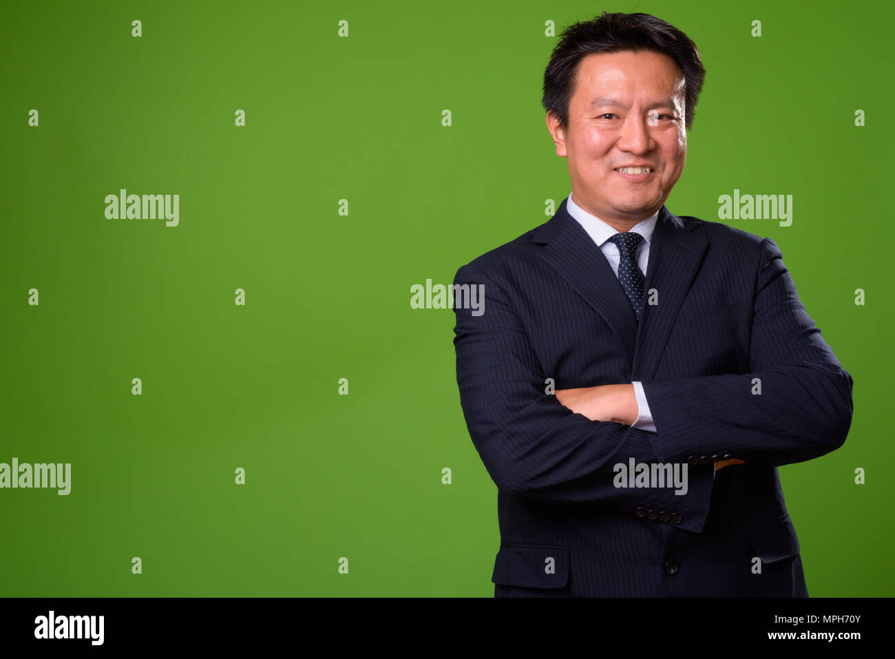 Maturo imprenditore giapponese contro lo sfondo di colore verde Foto Stock