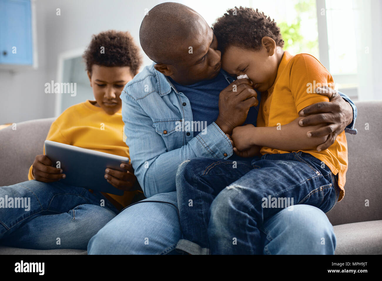 Amare giovane padre tergi naso del suo figlio di pianto Foto Stock