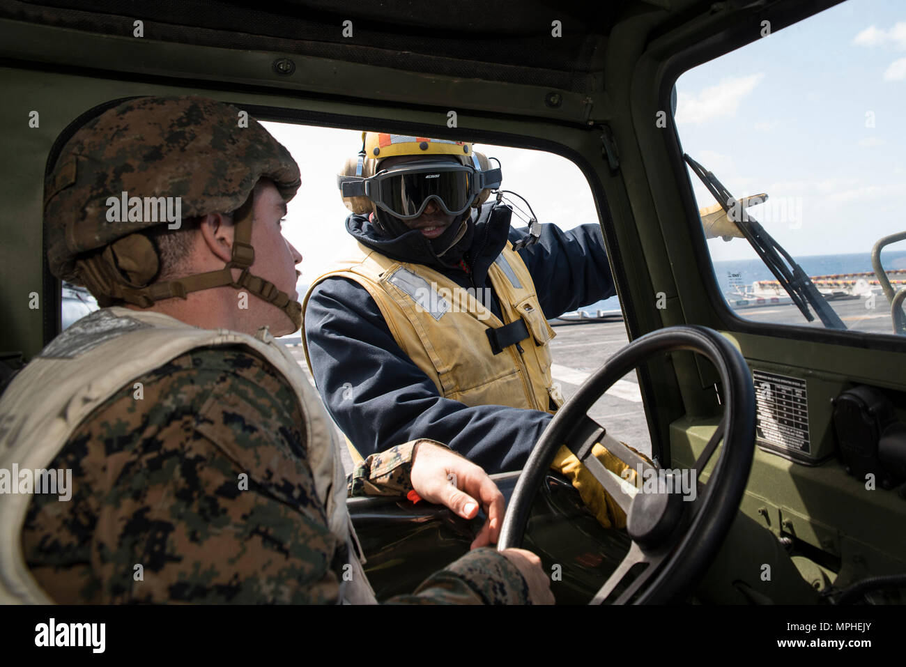 170315-N-XT039-064 Mare delle Filippine (15 marzo 2017) di aviazione di Boatswain Mate (manipolazione) 1a classe Jerome Dunkley, dalla Convenzione di Montego Bay, Giamaica, assegnato a Amphibious Assault nave USS Bonhomme Richard (LHD 6), dirige il cpl. Nathan Banta, da Versailles, Ill., assegnato al battaglione di team di atterraggio (BLT) 2/5 E BATTERIA artiglieria, durante internamente un veicolo trasportabile, sciopero luce variante (ITV-LSV) sul carico sul ponte di volo di Bonhomme Richard a sostegno dell'integrazione anfibio formazione (AIT). AIT è progettato per integrare tutti gli elementi del Bonhomme Richard Expeditionary Strike gruppo (BHR ESG) Foto Stock