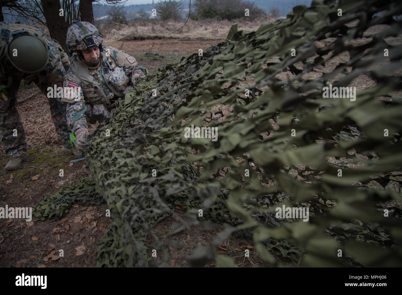 Un soldato lettone del 1 ° brigata lettone fissa camouflage netting mentre copre una brigata tactical operations center durante l'esercizio Allied spirito vi al settimo Esercito di formazione del comando Hohenfels Area Formazione, Germania, Marzo 15, 2017. Esercizio Allied spirito vi comprende circa 2.770 partecipanti da 12 NATO e partner per la pace delle nazioni, e degli esercizi di tattica di interoperabilità e prove di comunicazione sicura entro i membri dell alleanza e nazioni partner. (U.S. Esercito foto di Spc. Randy Wren) Foto Stock