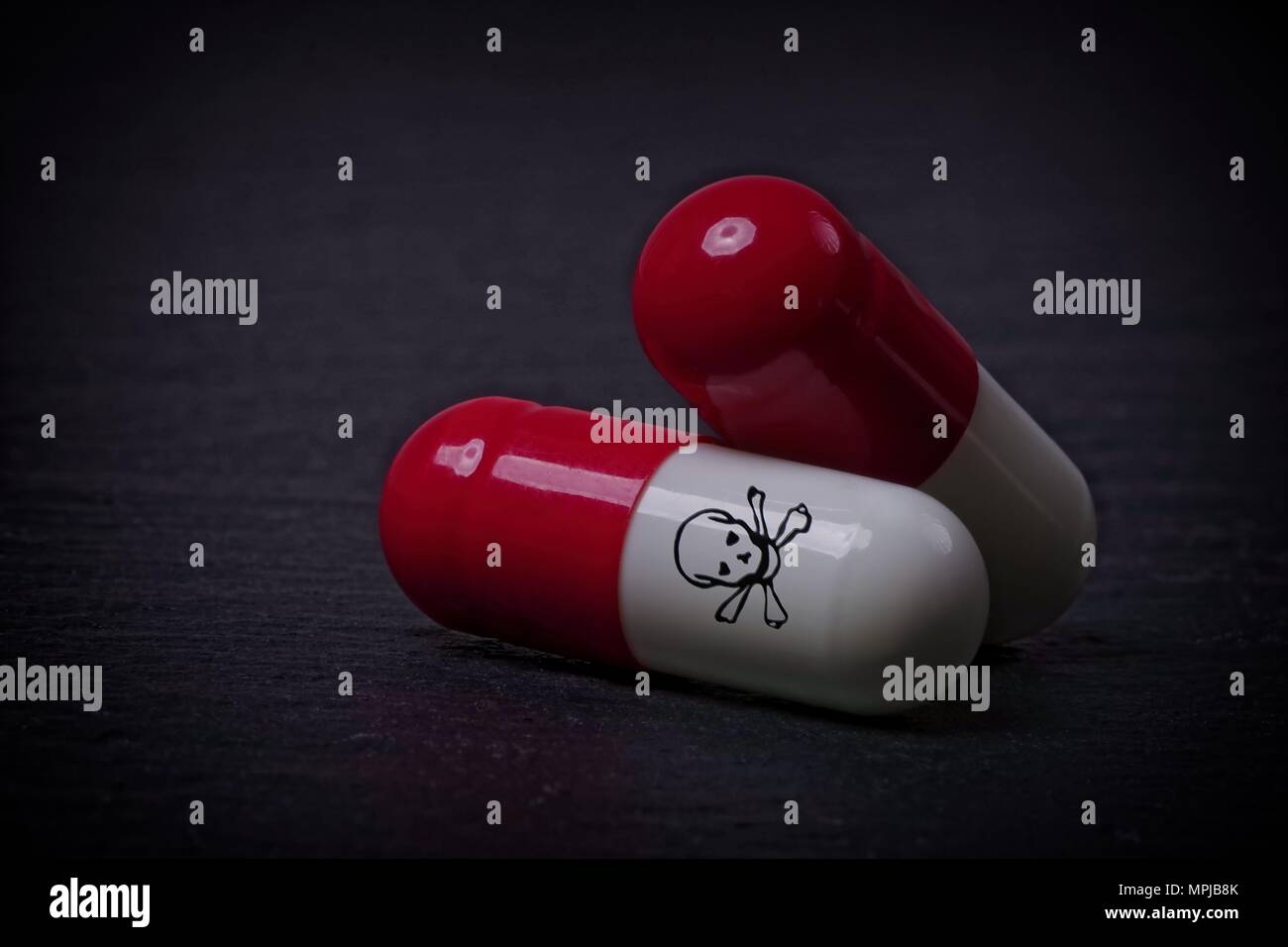 Le capsule di farmaco con cranio e crossbone sulla pietra scuro dello sfondo. Foto Stock